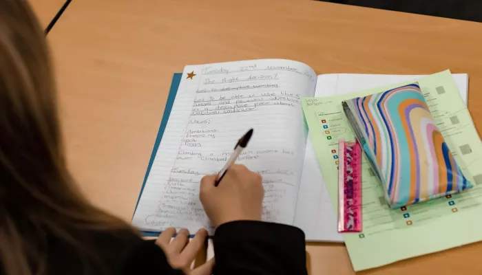 A pupil writes in an exercise book