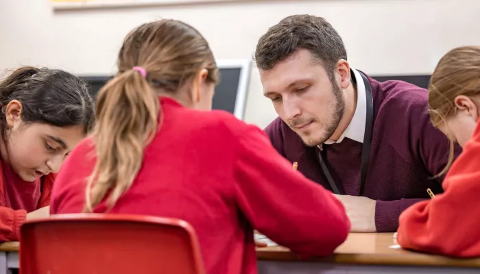 A tutor and pupil are looking closely at a piece of work.