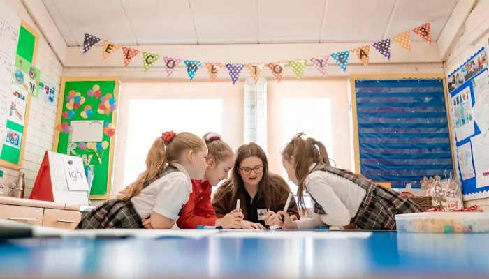 A tutor and pupils are enthusiastically studying some writing.