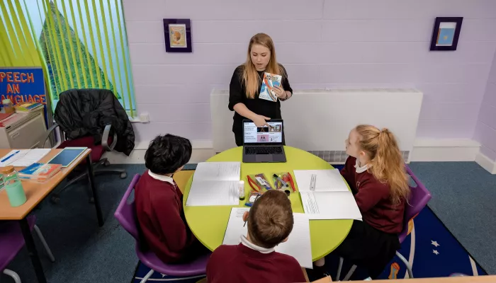 A tutor shows a group of pupils a page on a website relevant to their work