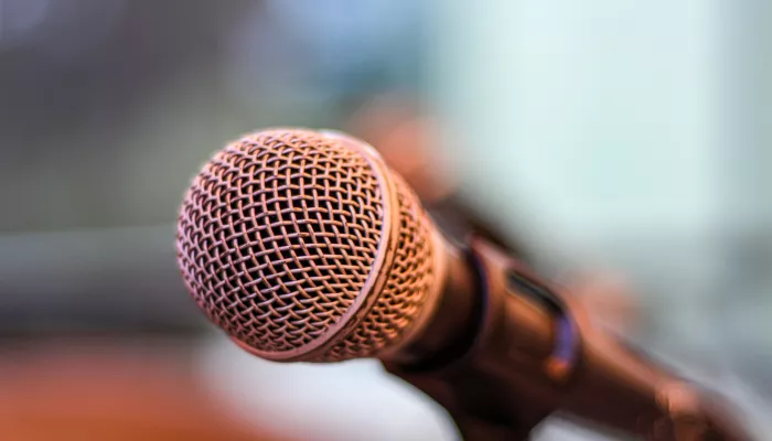 A close-up image of a microphone against a blurred background.