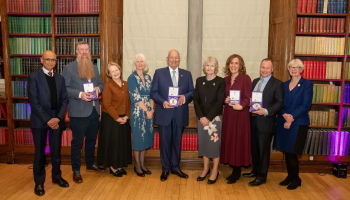 Recipients of the University of Manchester Medal of Honour standing in a line with their awards 