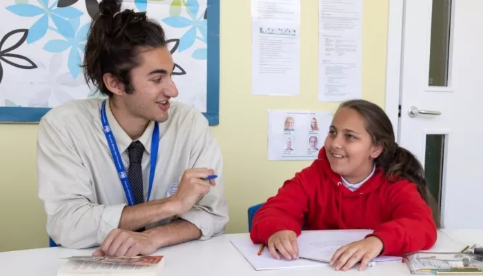 A tutor and a pupil smile during a tuition session.