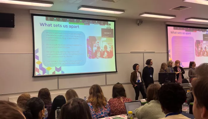 A Tutor Trust team presenting at the front of a busy lecture theatre