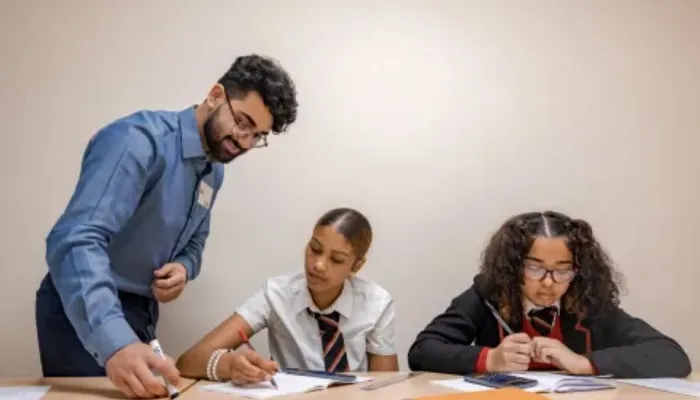 a male tutor with a beard and glasses with two year 9 girls