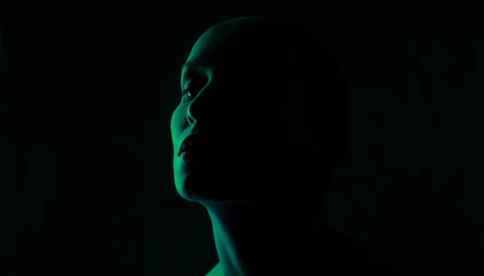 silhouette of a woman's head in low green light