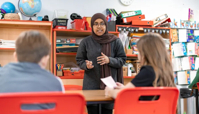 Tutor faces 2 pupils in a classroom