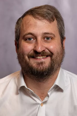 Chief Executive Officer Ed Marsh, is a powerful advocate for social mobility and championing the rights of those who are underserved. He is pictured wearing a white open-necked shirt, and is smiling to camera.