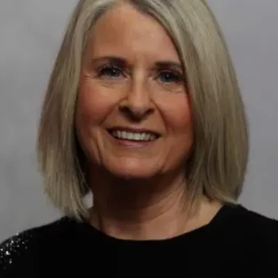 Joanne Meredith, Director of Tutoring Plus, enjoys being part of a team that makes such a difference to young people's lives. Jo has shoulder length blonde hair and is wearing a black jumper. She is smiling at the camera. 
