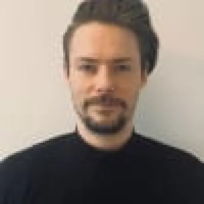 Will is a keen advocate of social mobility, and uses his role to help students from backgrounds similar to our tutees, to have the opportunity to tutor with us, Will is dark-haired with a beard and moustache. He is wearing a black jumper.