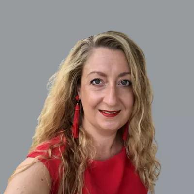 Claire has blonde hair and is wearing a red dress. She is smiling for the camera