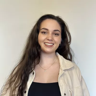 Hannah Cunningham is a former teacher who enjoys making a positive impact on young people's lives. Hannah has long brown hair and is wearing a black jumper.