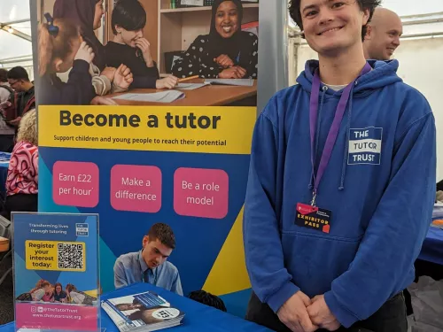 One of our Recruitment Team drums up interest at the University of Liverpool jobs fair. The member of staff is standing in front of a pull-up banner with details of the role. He is wearing a blue Tutor Trust hoodie.