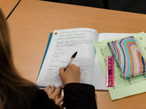 A pupil writes in an exercise book