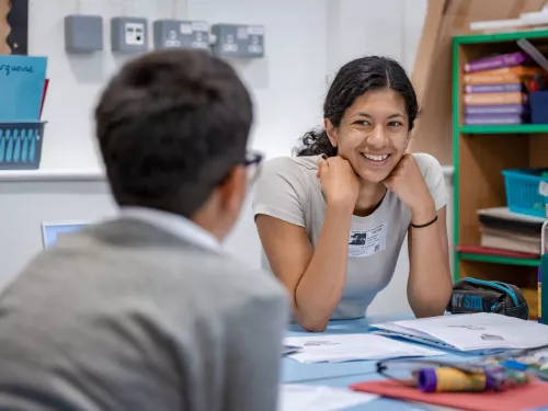 A tutor smiles at a young pupil