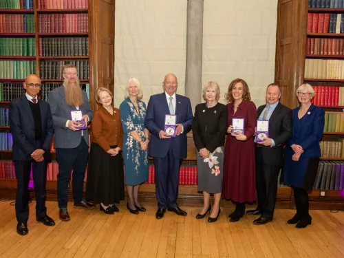 Recipients of the University of Manchester Medal of Honour standing in a line with their awards 