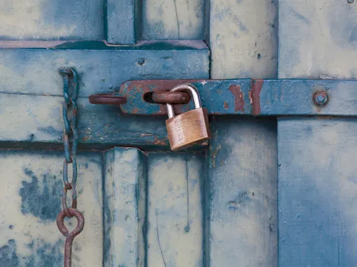 a brass padlock on a worn blue painted door
