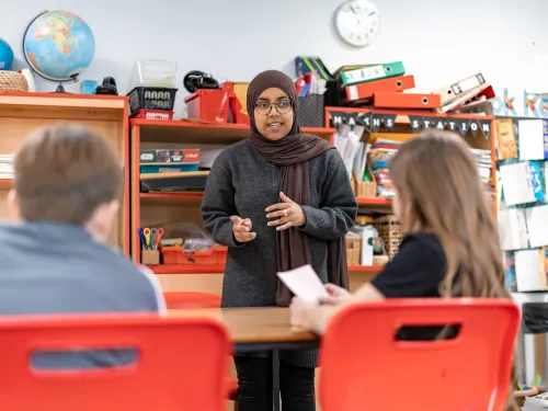 A woman in glasses and a headscarf teaches in a primary school